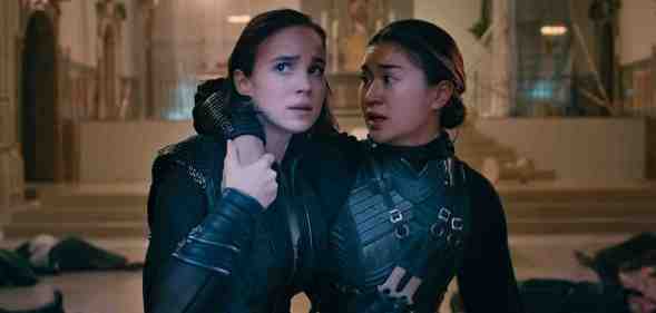 A still from Netflix series Warrior Nun showing actors Alba Baptista and Kristina Tonteri-Young as Ava and Beatrice wearing their warrior nun costumes; and Ava is supporting Beatrice in a room with bodies lying on the floor