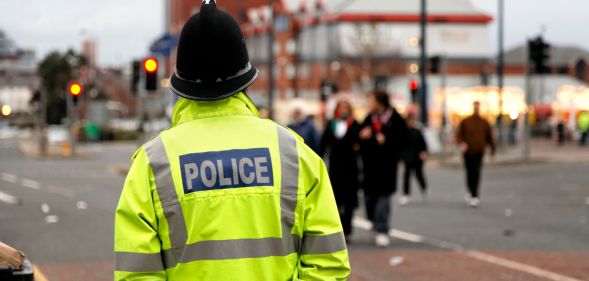 A policeman patrols in a high vis jacket around a city centre.