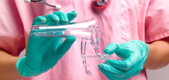 A doctor wearing a pink scrubs is holding equipment used in a cervix screening test