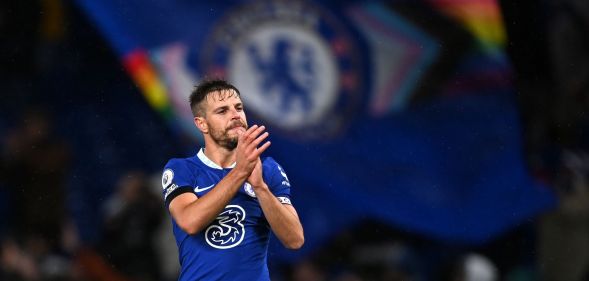 Chelsea player Cesar Azpilicueta claps during the end of a match while a Pride Chelsea flag waves in the background.