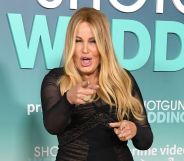 Jennifer Coolidge wearing a black dress at the Shotgun Wedding premiere, pointing at the camera with her mouth open.