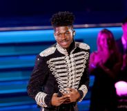 Lil Nas X performs at the 2022 Grammy Awards in a black and silver jacket.