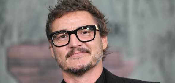 A close-up screenshot of actor Pedro Pascal wearing a black suit and glasses