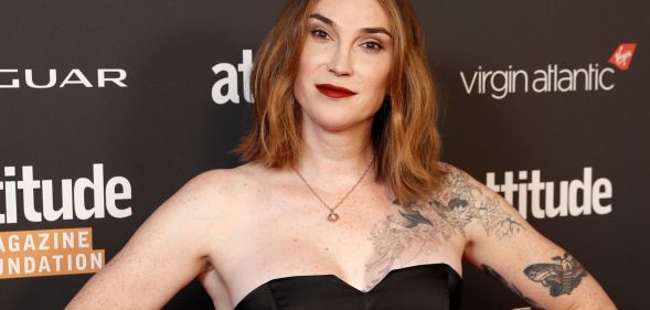 Trans author Juno Dawson wears a black dress with her hands on her hips