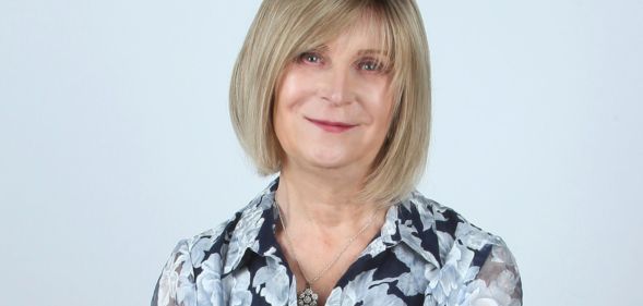 Steph Richards, founder of TransLucent, smiles at the camera while wearing a black and white floral print top