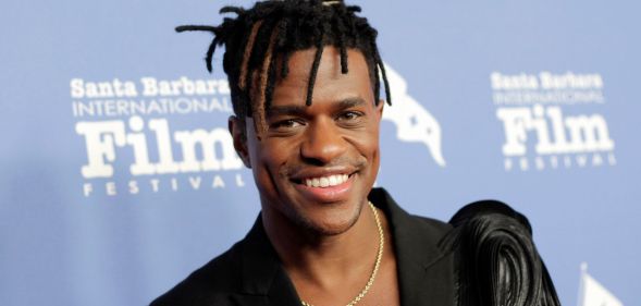 Jeremy Pop wears a black blazer and gold chain while smiling on the red carpet at the 38th Annual Santa Barbara International Film Festival.