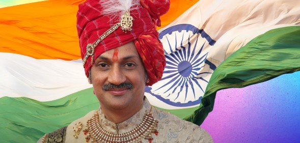 Prince Manvendra Singh Gohil, a smiling man wearing a gold top, red jewelled necklace and red turban with a feather.