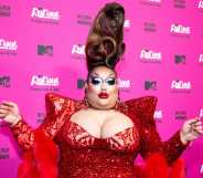 A photo of drag queen Mistress Isabelle Brooks from RuPaul's Drag Race season 15 wearing an over-the-top red dress as she poses for the cameras at an MTV publicity event