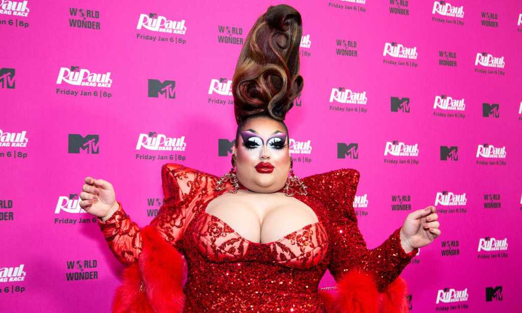 A photo of drag queen Mistress Isabelle Brooks from RuPaul's Drag Race season 15 wearing an over-the-top red dress as she poses for the cameras at an MTV publicity event