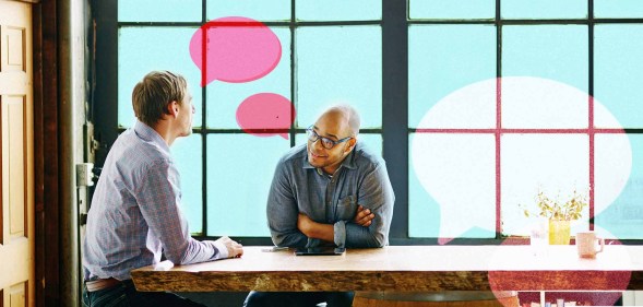 Two men are speaking at a table. One man is wearing classes and looking at the other man. There are illustrations of speech bubbles.