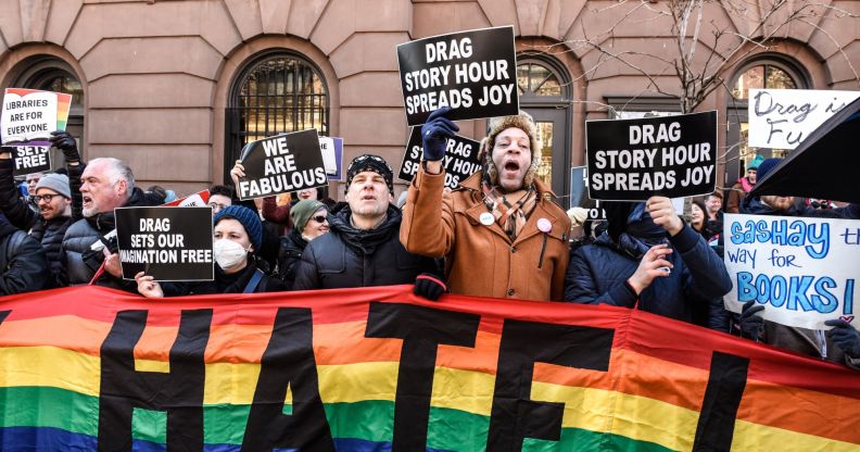 Counter-protestors hold up a rainbow banner and signs in support of the LGBTQ+ community while standing in solidarity with a Drag Story Hour event