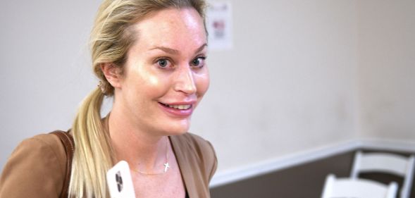 Christina Pushaw, in a brown cardigan, poses for a photo.