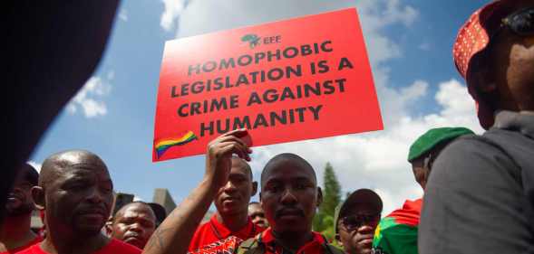 A proptester holds a sign that reads: homophobic legislation is a crime against humanity