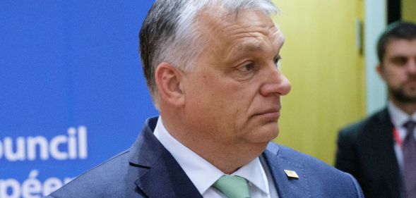 Viktor Orban, wearing a blue suit and teal tie, looks off.