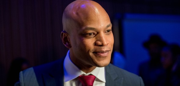 Maryland governor Wes Moore wearing a red tie and dark blue suit on a dark blue background