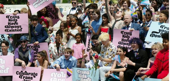 A group of trans youth hold signs of trans solidarity.