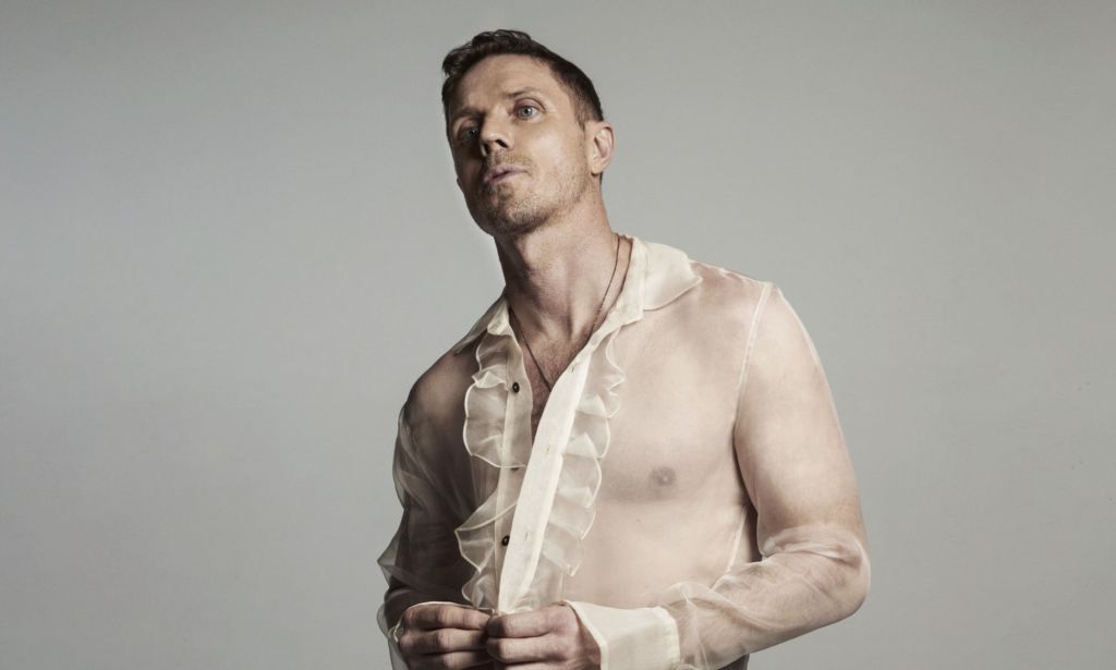 Jake Shears wears a see-through, frilled white top in a promotional image for his new album Last Man Dancing.