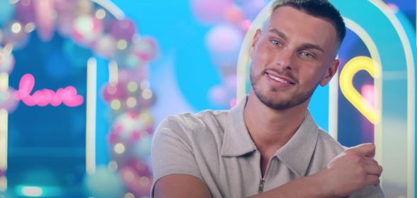 Love Island 2023 contestant George Fensom wears a grey shirt as he sits down for an interview