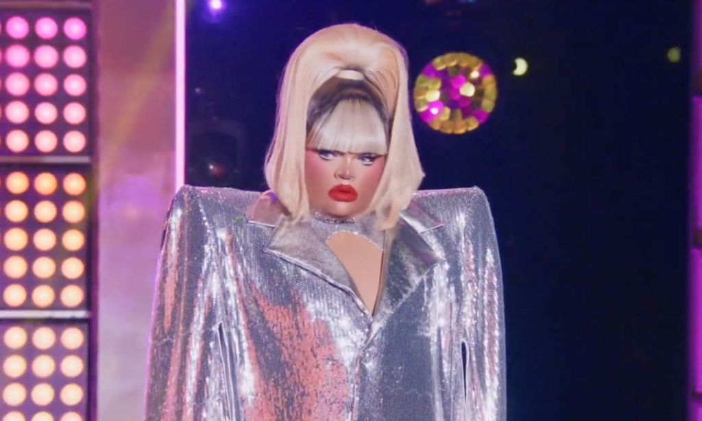 Kandy Muse in a silver coat and high blonde ponytail ready to perform the final lip sync for the crown against Jimbo.