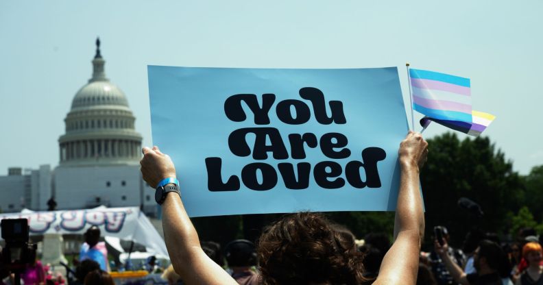 A person holds up a sign reading 'you are loved' during a demonstration in favour of the trans community amid legislative attacks on trans youth being able to access gender-affirming care