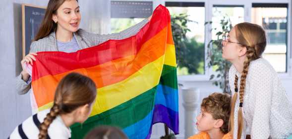 LGBTQ education in action as a teacher shows her class a Pride flag.