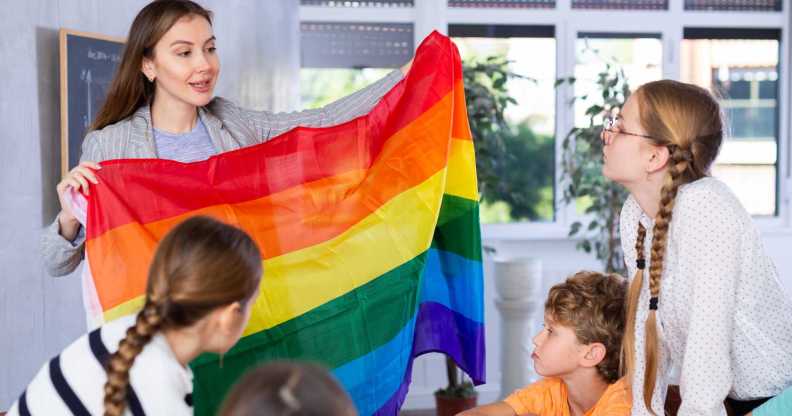 LGBTQ education in action as a teacher shows her class a Pride flag.