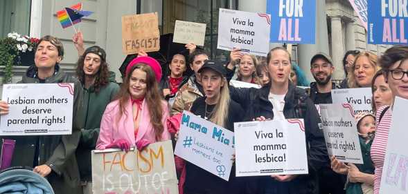 Protestors have rallied in London against Italy’s cruel move to strip lesbian mum’s who did not give birth to their child from birth certificates. 