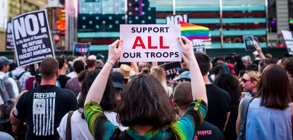 A person holds up a sign reading 'support all troops' during a protest against the trans military ban