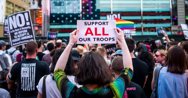 A person holds up a sign reading 'support all troops' during a protest against the trans military ban