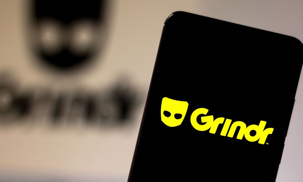 This is an image of a mobile phone with the Grindr logo in bright yellow.