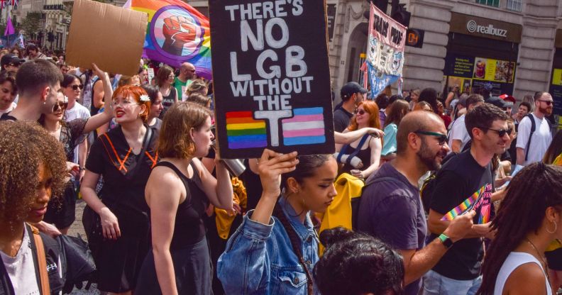 A protestor holds a sign reading "There's no LGB without the T."