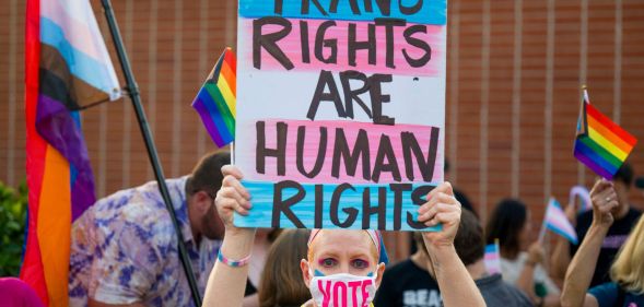 Person holds up a sign reading "trans rights are human rights" at a protest in California