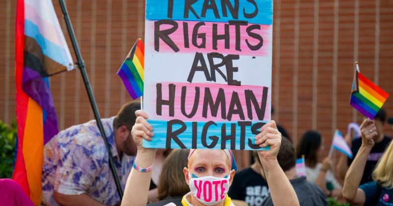 Person holds up a sign reading "trans rights are human rights" at a protest in California