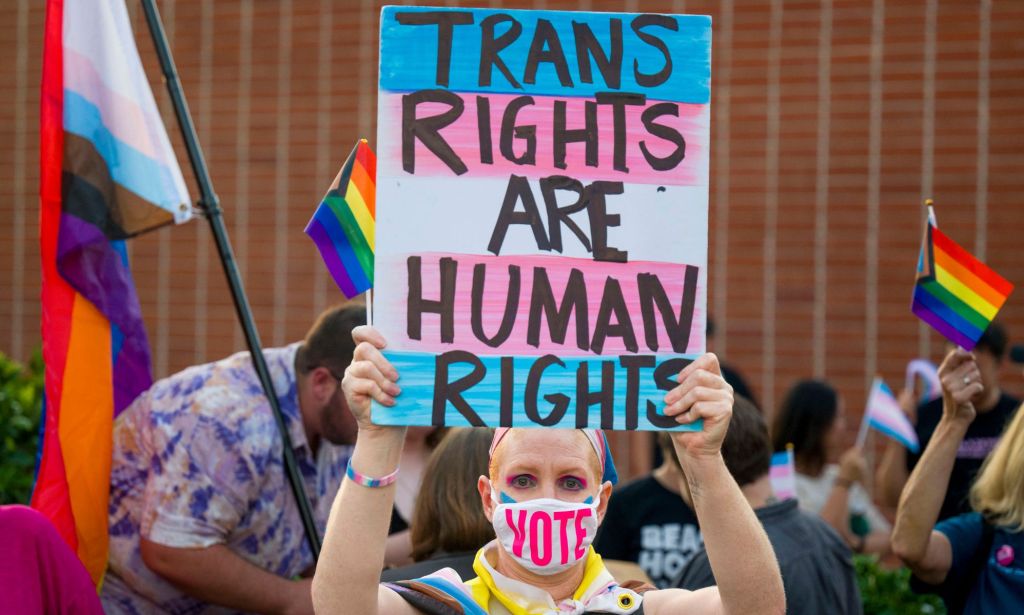 Person holds up a sign reading "trans rights are human rights" at a protest in California