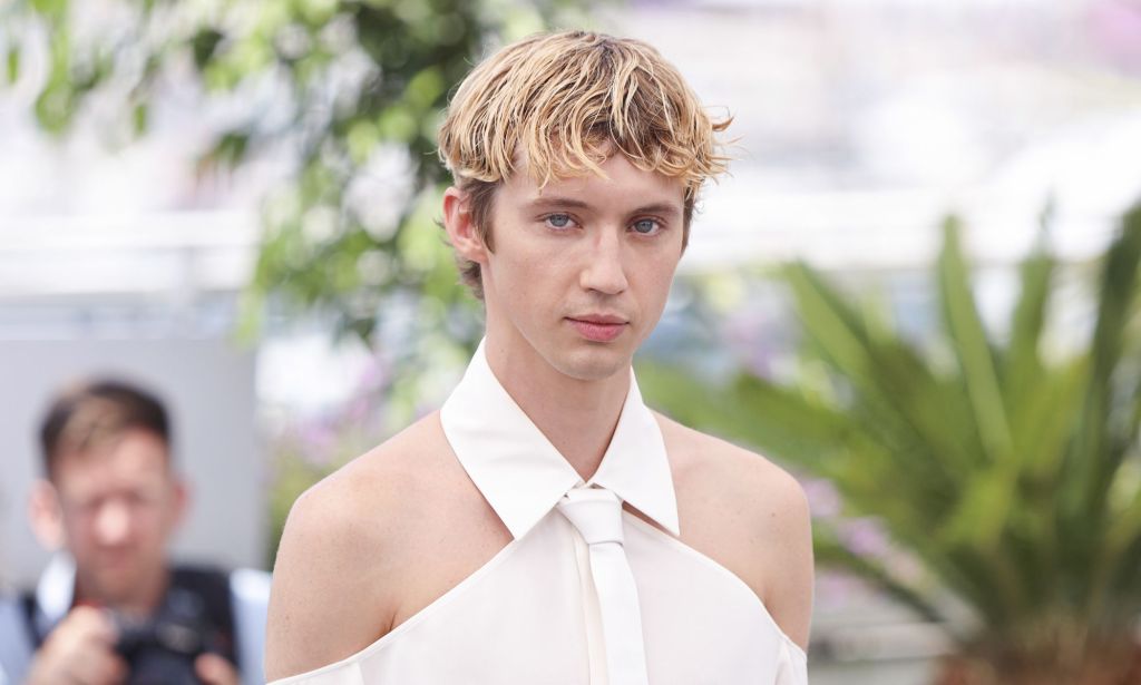 Troye Sivan in a white shoulder-less shirt.