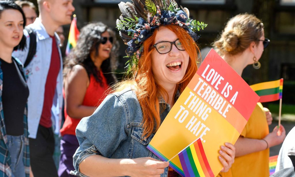 An LGBTQ+ activist holds a sign saying 'love is a terrible thing to hate'