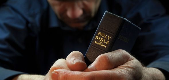 A man prays over a Bible.