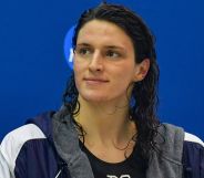 A woman with wet hair smiles during a post-swimming match photoshoot.