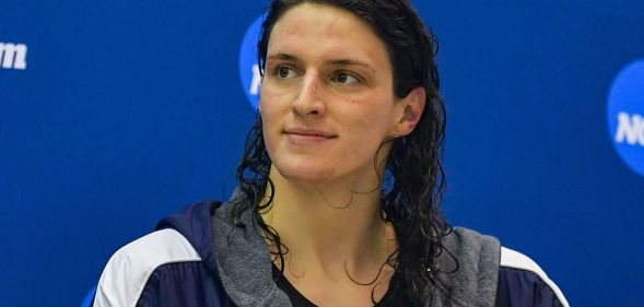 A woman with wet hair smiles during a post-swimming match photoshoot.