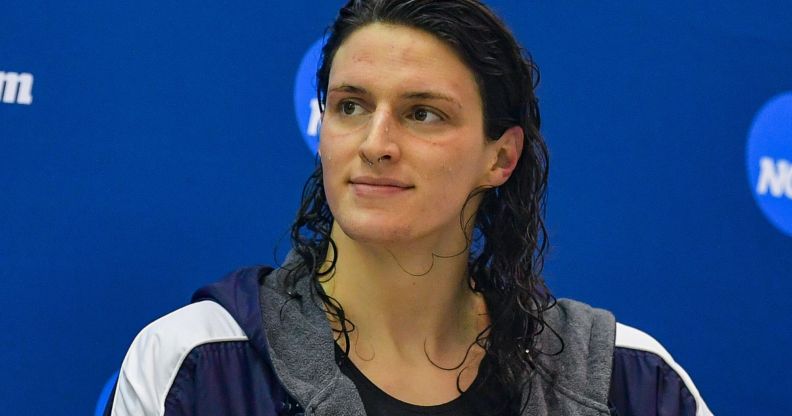 A woman with wet hair smiles during a post-swimming match photoshoot.