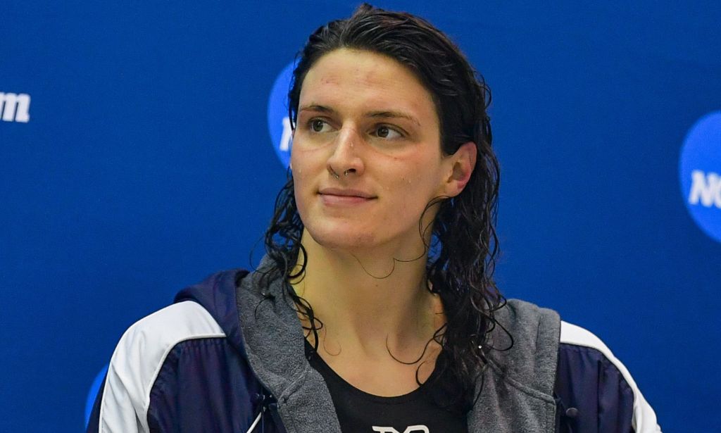 A woman with wet hair smiles during a post-swimming match photoshoot.