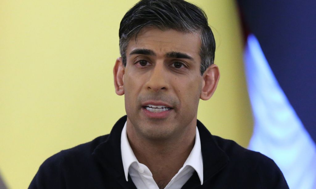 Rishi Sunak, speaking infront of a yellow flag during a news conference.