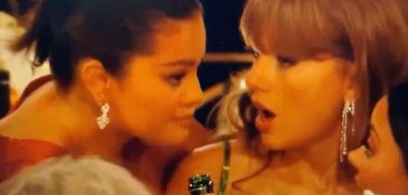 Selena Gomez leans down to talk to Taylor Swift during a now viral interaction at the 2024 Golden Globes