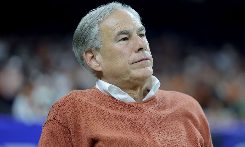 Texas governor Greg Abbott is pictures wearing a light colours shirt and an orange jumper on top