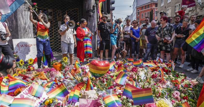 People with Pride flags stand near the London pub and lay flowers on June 25, 2022, in the aftermath of a shooting outside pubs and nightclubs in central Oslo killing two people and injuring many.
