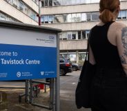 A person in a tank top stands outside infront of the Tavistock Centre sign.