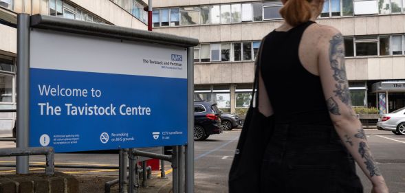 A person in a tank top stands outside infront of the Tavistock Centre sign.