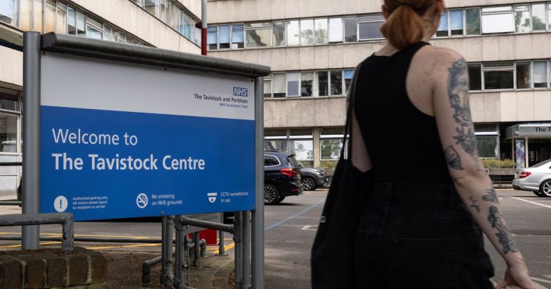 A person in a tank top stands outside infront of the Tavistock Centre sign.