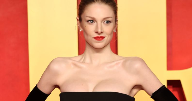 Hunter Schafer with her hands on her hips posing at a Vanity Fair red carpet event.