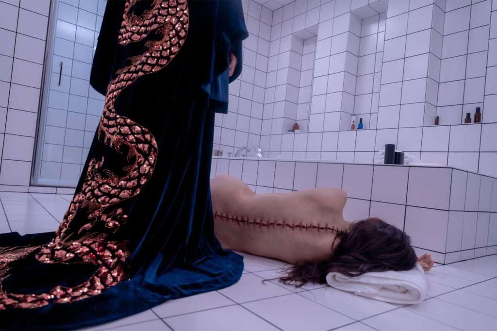 The Substance still, a woman lying on the bathroom floor with her back stitched up.